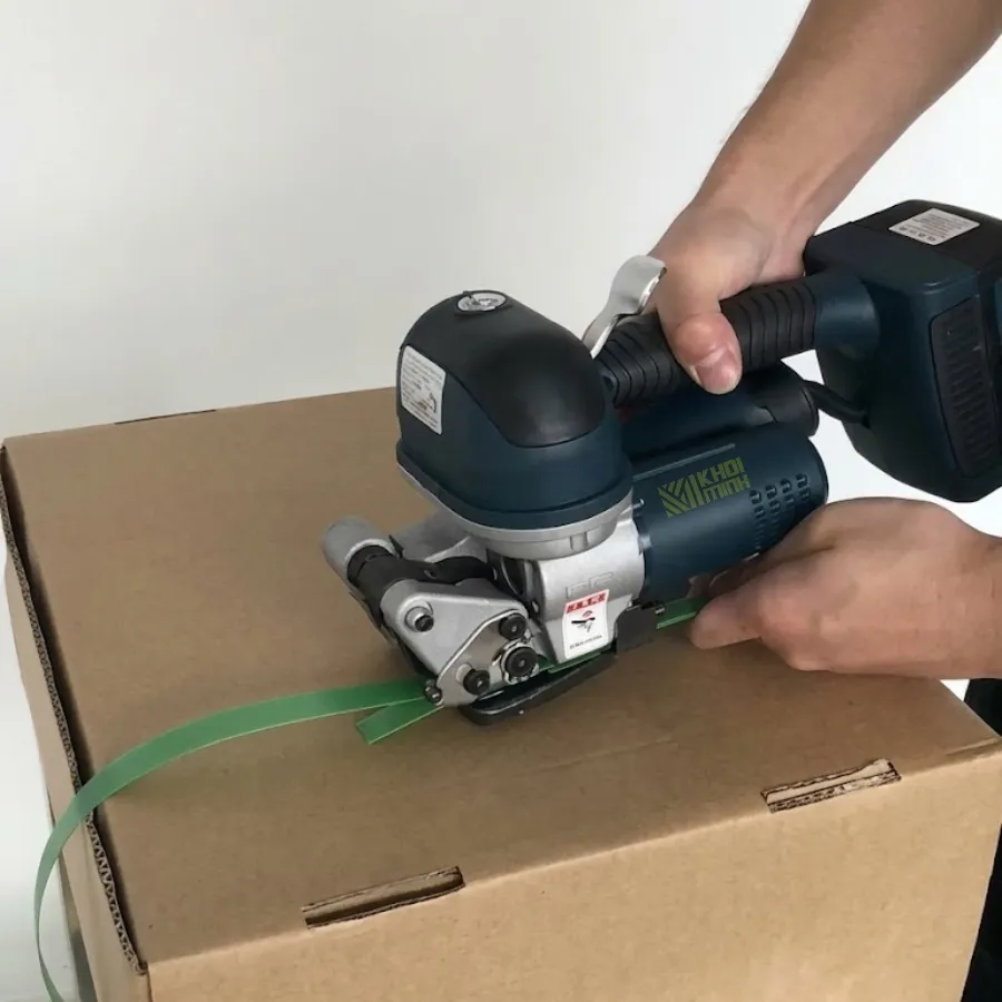 Khách hàng đang dùng máy đóng đai pin DD19A siết dây đai nhựa trên thùng carton sau khi được hướng dẫn