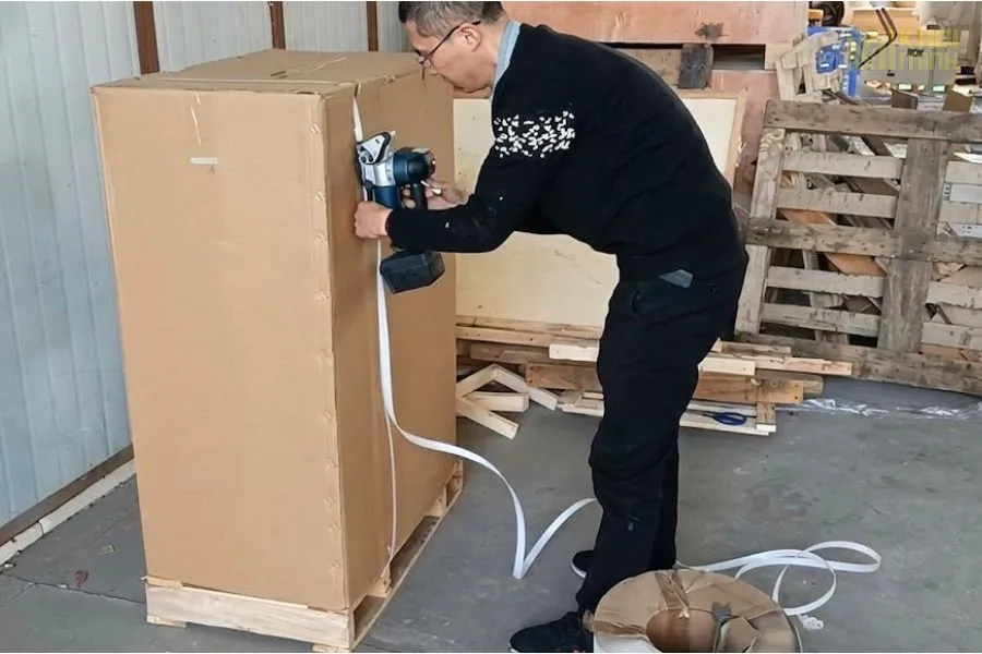 Khách hàng thao tác đai kiện hàng lớn đặt trên pallet gỗ bằng máy đóng đai chạy pin DD19A cung cấp bởi Điện máy Khôi Minh
